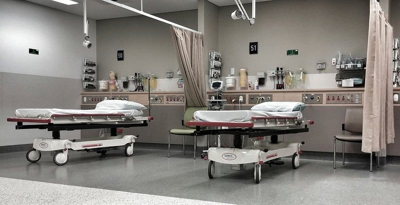 Inpatient bay with hospital trolleys, privacy curtains and wall-mounted medical gas panels